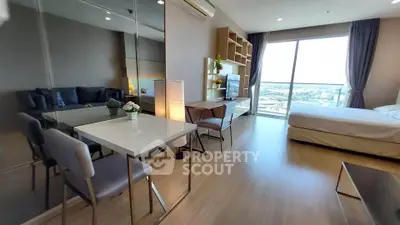 Modern studio apartment with open layout, featuring a cozy living area and large windows with city views.