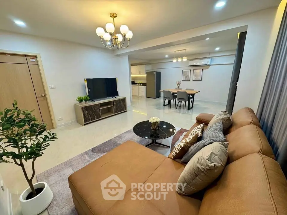 Spacious modern living room with open kitchen, elegant decor, and cozy seating area.