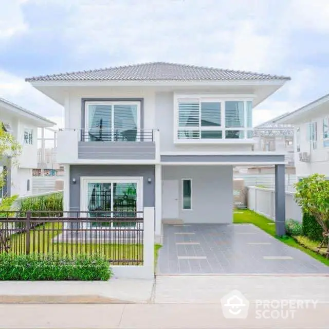 Modern two-story house with sleek design and spacious driveway in suburban neighborhood.