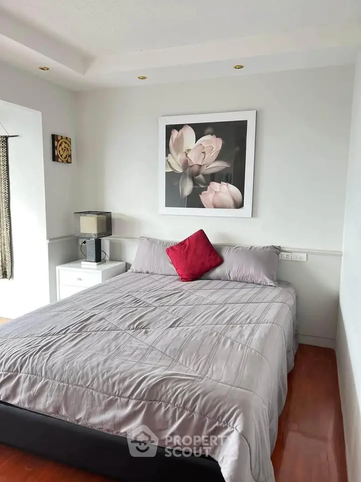 Cozy bedroom with elegant decor and floral artwork, featuring a comfortable bed and stylish lighting.