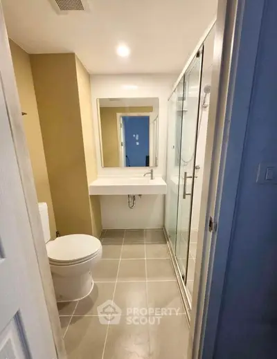 Modern bathroom with glass shower and sleek vanity in contemporary apartment.