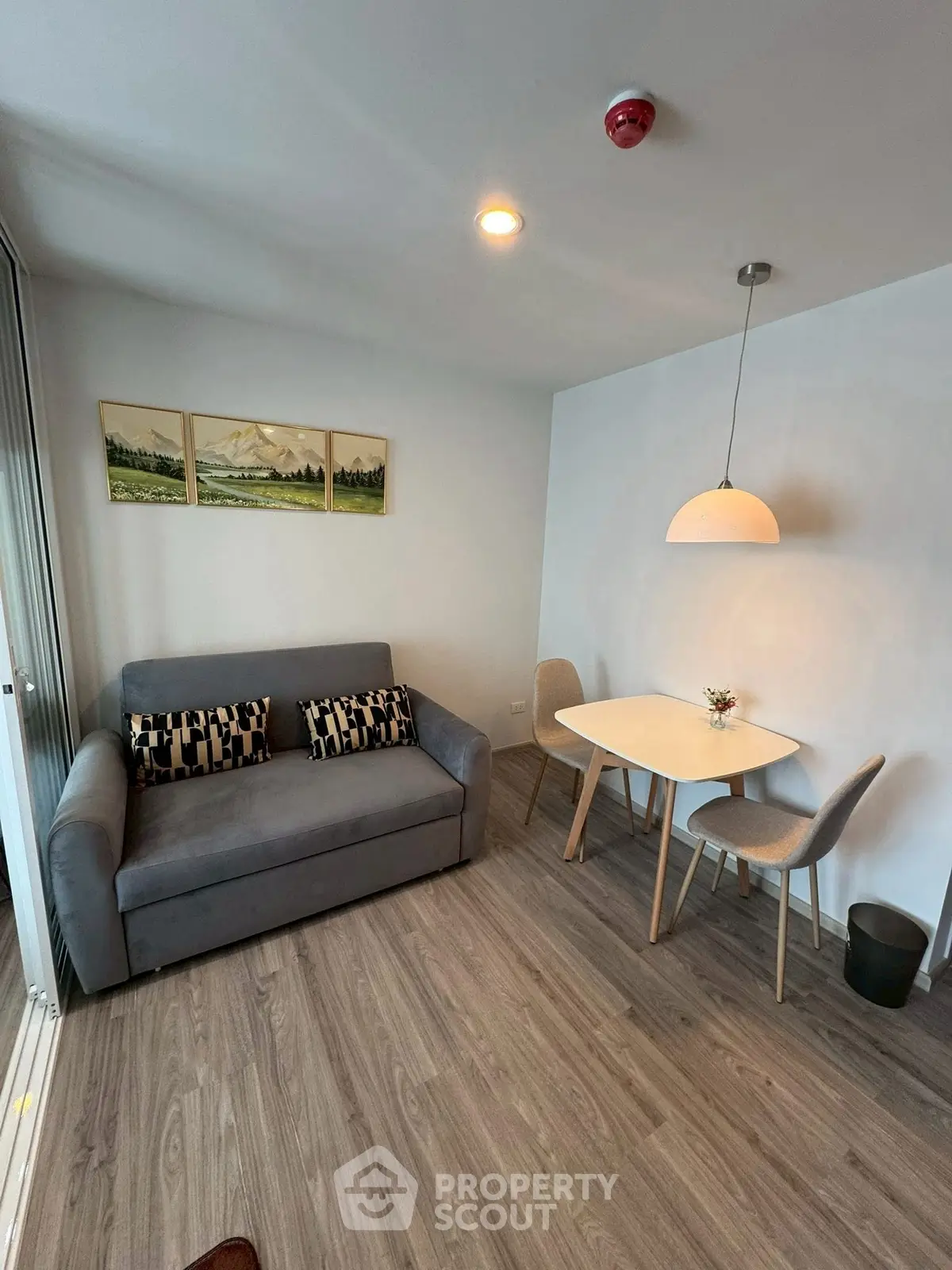 Modern living room with cozy sofa and dining area, featuring elegant decor and wooden flooring.