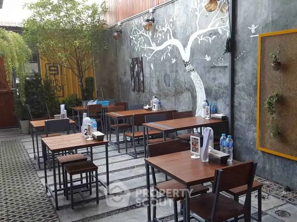 Charming outdoor dining area with artistic wall mural and cozy seating, perfect for a cafe or restaurant.