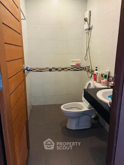 Modern bathroom with sleek fixtures and tiled walls, featuring a toilet and sink.