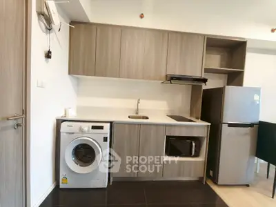 Modern kitchen with washing machine, microwave, and fridge in compact layout.