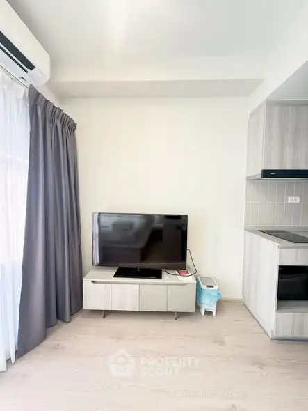 Modern living room with sleek TV setup and stylish kitchen area, perfect for contemporary living.