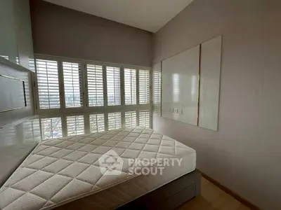 Modern bedroom with large windows and city view, featuring a comfortable mattress and sleek design.