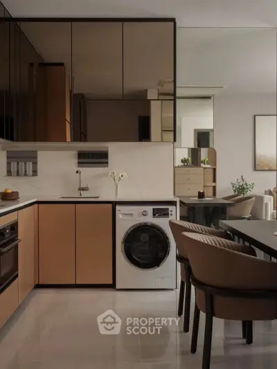 Modern kitchen with sleek cabinetry and built-in appliances, featuring a washing machine and elegant dining area.
