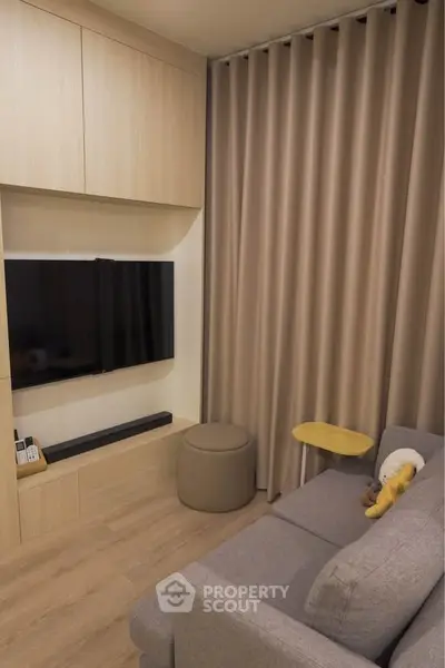 Cozy living room with modern decor, featuring a sleek TV setup and comfortable seating.