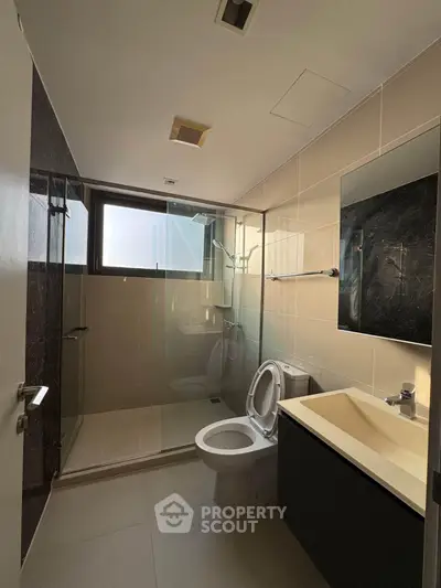 Modern bathroom with glass shower and sleek fixtures in a contemporary apartment.