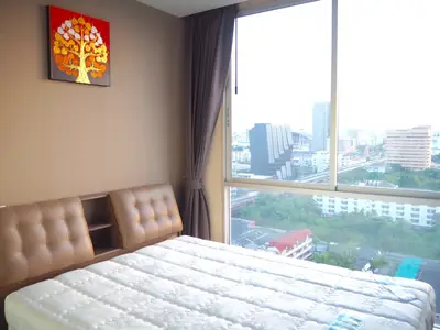 Bright bedroom with large window offering stunning city view, modern decor, and cozy ambiance.