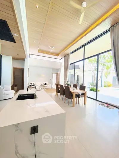 Luxurious open-plan living and dining area with high ceilings and large windows offering garden views.