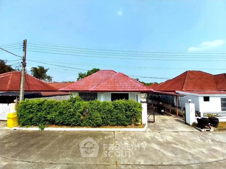 Charming single-story house with red roof and lush greenery in a serene neighborhood.