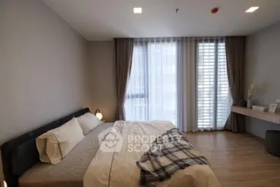Spacious bedroom with modern decor and large window for natural light.