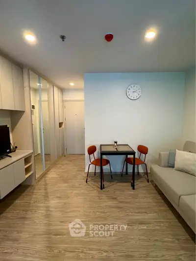 Modern living room with stylish furniture and wooden flooring, featuring a cozy dining area and wall-mounted TV.