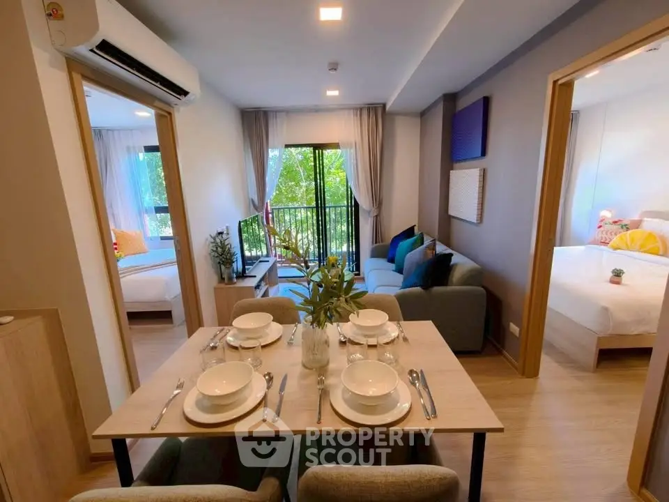 Modern open-plan living room with dining area and large windows in a stylish apartment.
