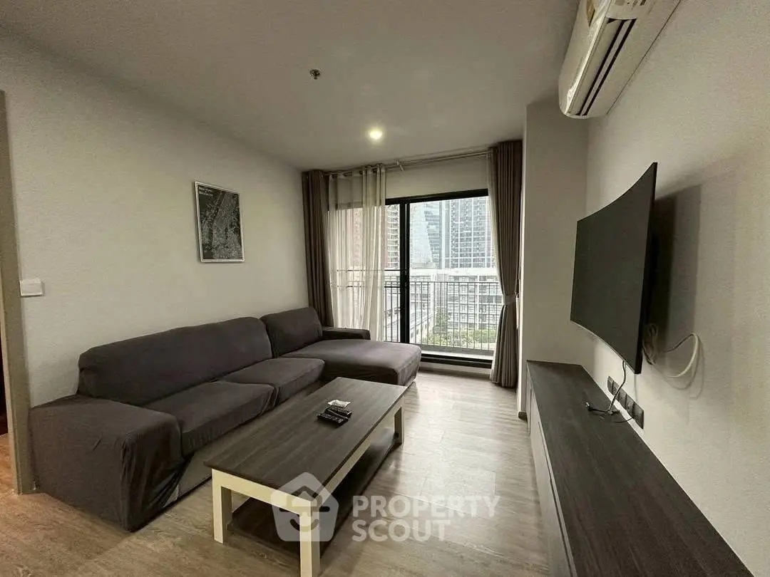 Modern living room with sleek furniture and city view balcony in high-rise apartment.
