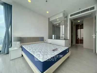 Modern bedroom with large window and city view, featuring a stylish bed and sleek design.
