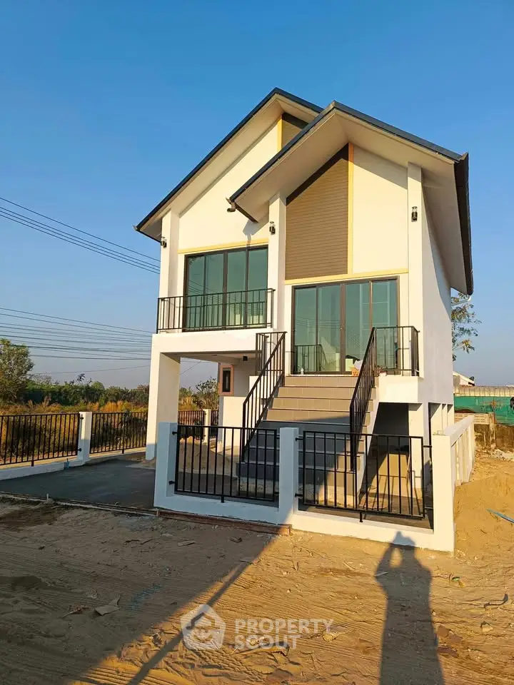 Modern two-story house with large windows and balcony, set in a serene suburban area.