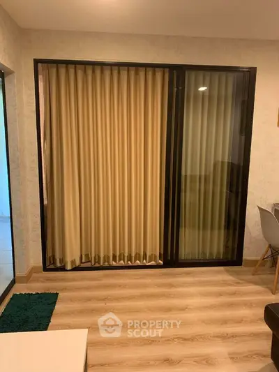 Cozy living room with wooden flooring and sliding glass doors leading to a balcony.