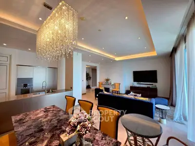 Luxurious open-plan living room with elegant chandelier and modern kitchen