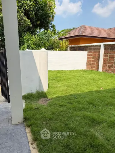Charming backyard with lush green lawn and privacy wall, perfect for outdoor relaxation.