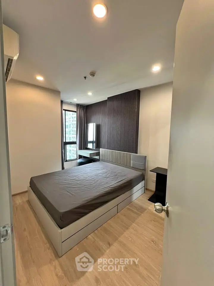 Modern bedroom with stylish decor and city view, featuring a comfortable bed and sleek furnishings.