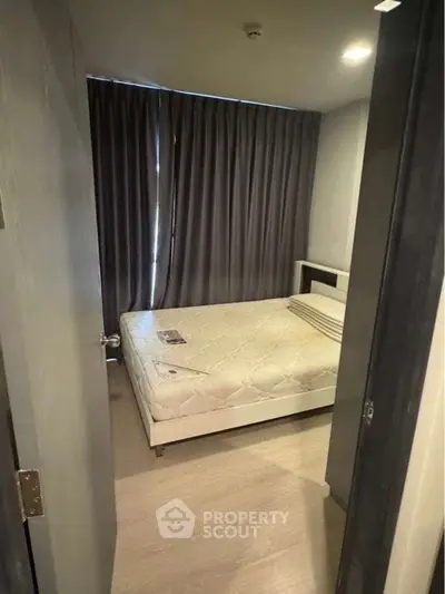 Cozy bedroom with minimalist decor and large window curtains, perfect for restful nights.