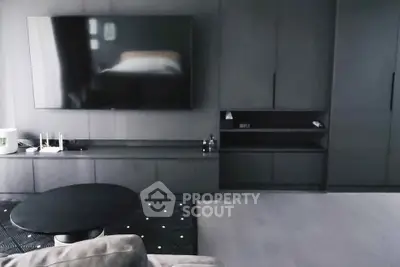 Modern living room with sleek black furniture and large wall-mounted TV