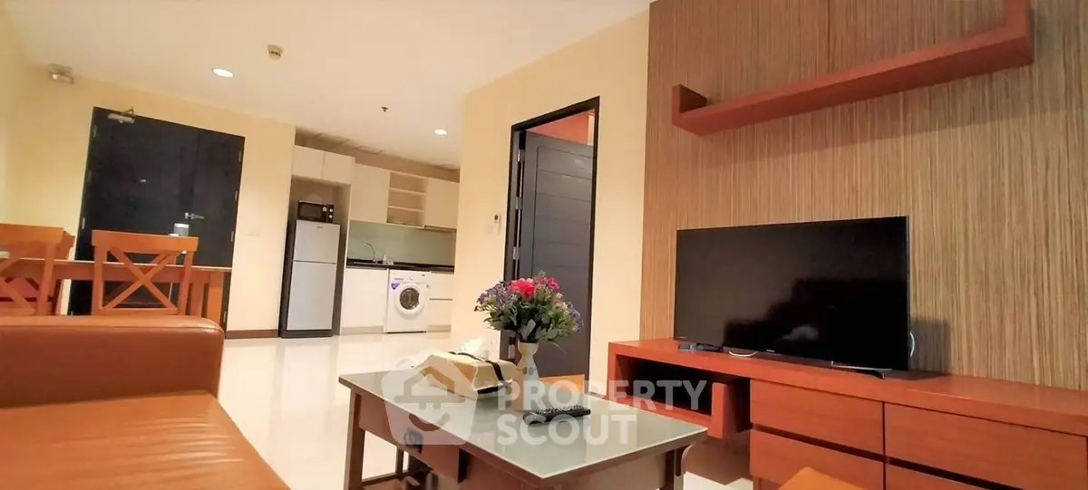 Modern living room with open kitchen, featuring sleek furniture and appliances for a cozy urban lifestyle.