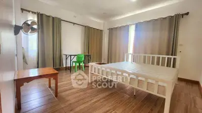 Spacious bedroom with wooden flooring and ample natural light.