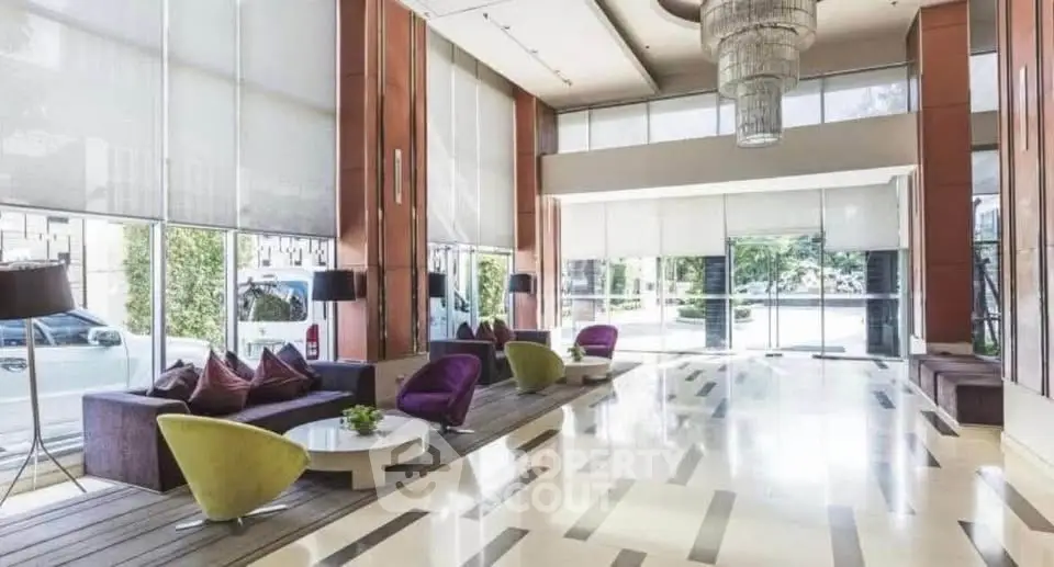 Luxurious lobby with modern seating and grand chandelier in upscale building entrance.