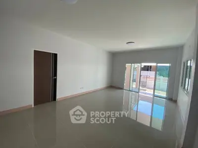 Spacious empty living room with large windows and shiny tiled floor.