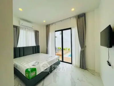 Modern bedroom with pool view, featuring a stylish bed and wall-mounted TV, ideal for luxury living.