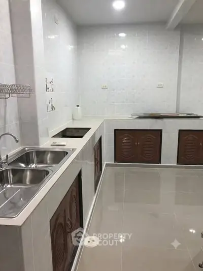 Spacious modern kitchen with sleek countertops and dual sinks, perfect for culinary enthusiasts.