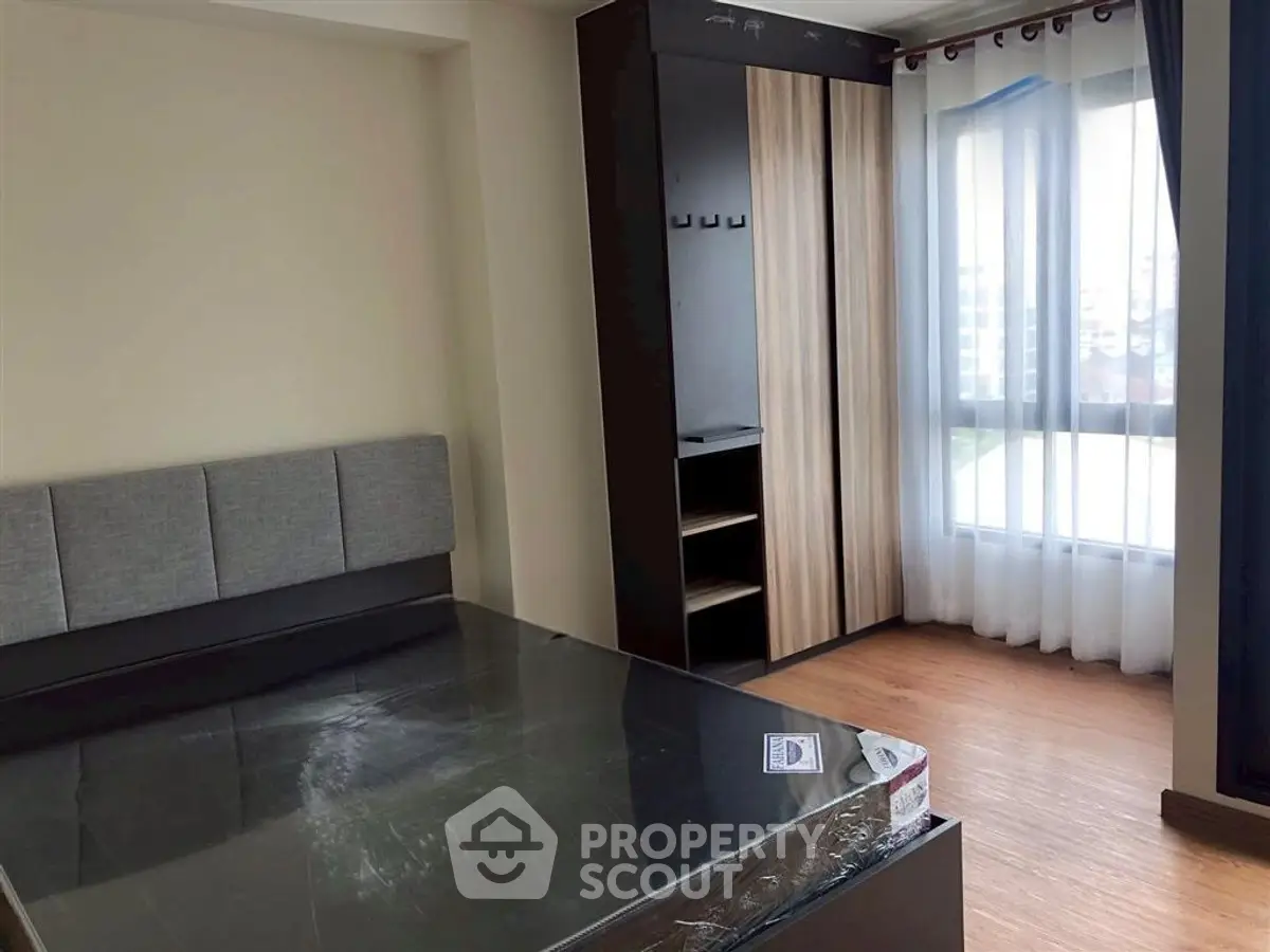Modern bedroom with large window and stylish wardrobe in a cozy apartment.