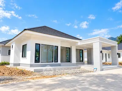 Modern single-story house with sleek design and large windows, set against a clear blue sky.