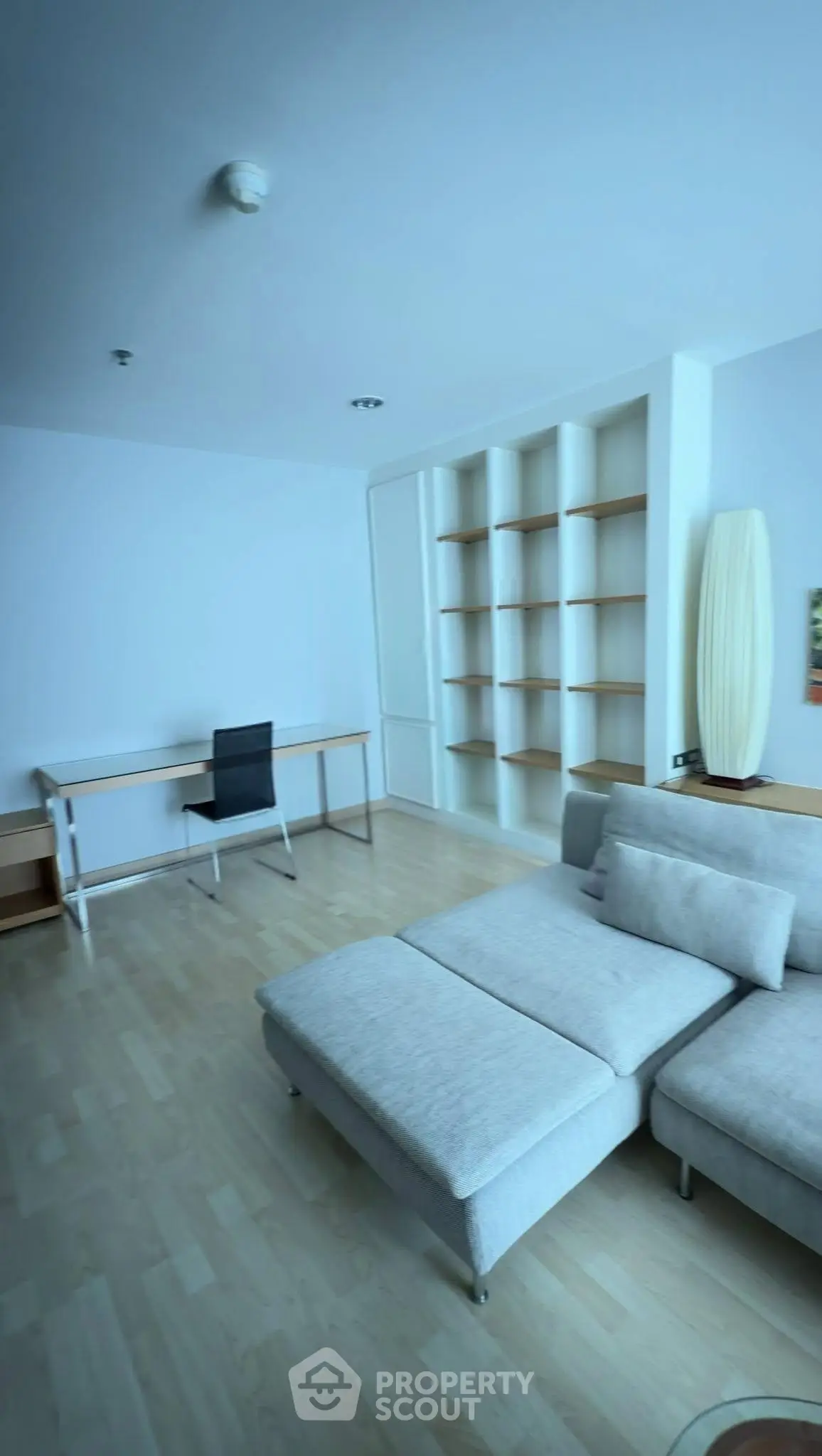 Spacious living room with modern furniture and built-in shelves, perfect for a cozy home office setup.
