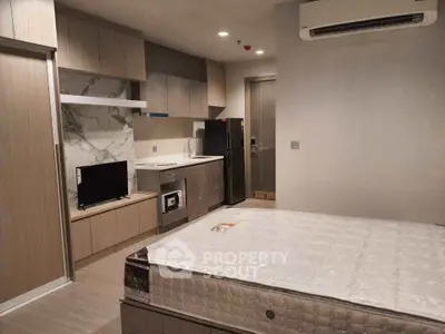 Modern studio apartment with sleek kitchen and cozy sleeping area.