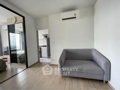 Modern apartment interior with cozy gray sofa and air conditioning, featuring sleek wooden flooring.