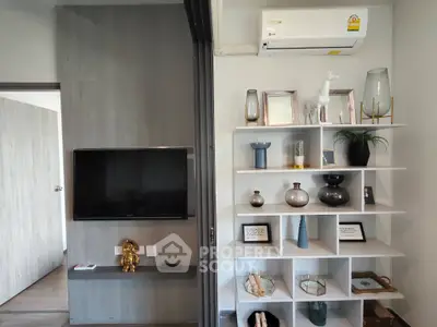 Modern living room with stylish shelving and wall-mounted TV, featuring elegant decor and air conditioning.