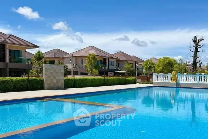 Luxurious residential community with stunning pool and elegant homes under clear blue sky.