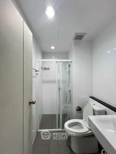 Modern bathroom with sleek shower and white fixtures in a contemporary apartment.