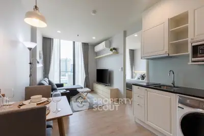 Modern open-plan living room with kitchen and city view, featuring stylish decor and natural light.