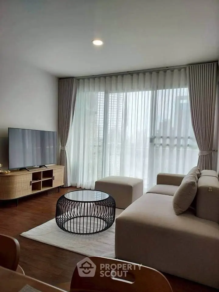 Modern living room with large windows, stylish furniture, and natural light.