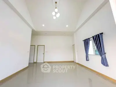 Spacious living room with high ceiling and modern lighting in a minimalist design.