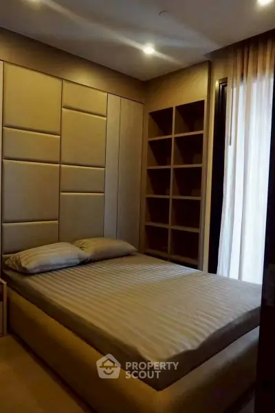 Cozy bedroom with modern design and built-in shelving, perfect for relaxation and storage.