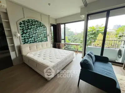 Spacious bedroom with large windows and balcony overlooking greenery, featuring a cozy bed and modern decor.
