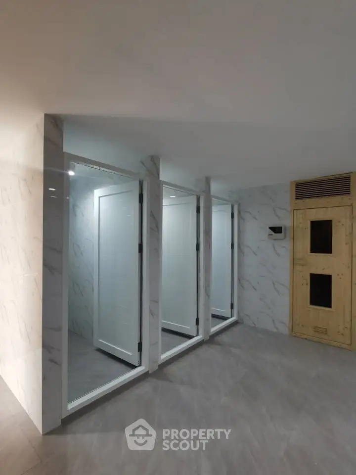Modern shared sauna and shower area with sleek marble walls and contemporary design.