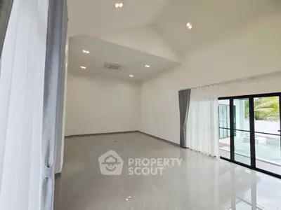 Spacious modern living room with high ceilings and large windows overlooking a pool area.